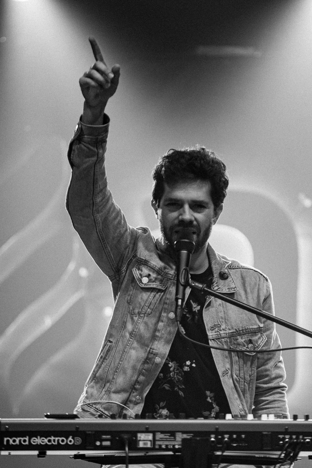 Matheus Rizzo no palco, em preto e branco, com o braço erguido