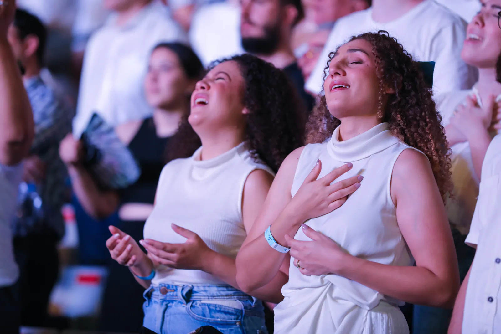 Público cantando de olhos fechados