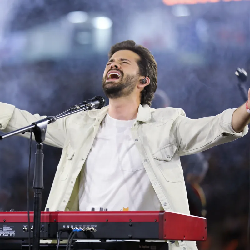 Matheus Rizzo ao vivo, braços abertos, cantando ao piano